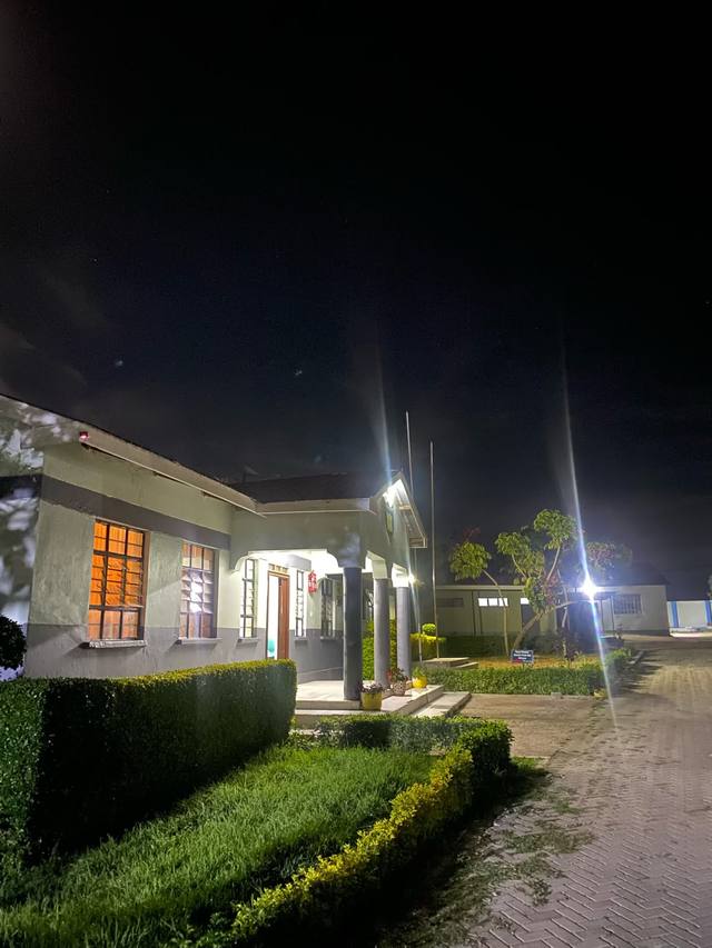 A lit school building with a covered entrance and hedges at night