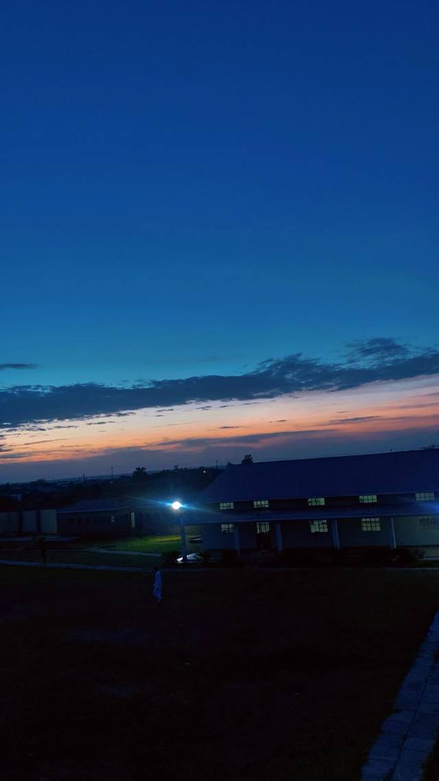 The campus at dusk with lights on in the buildings